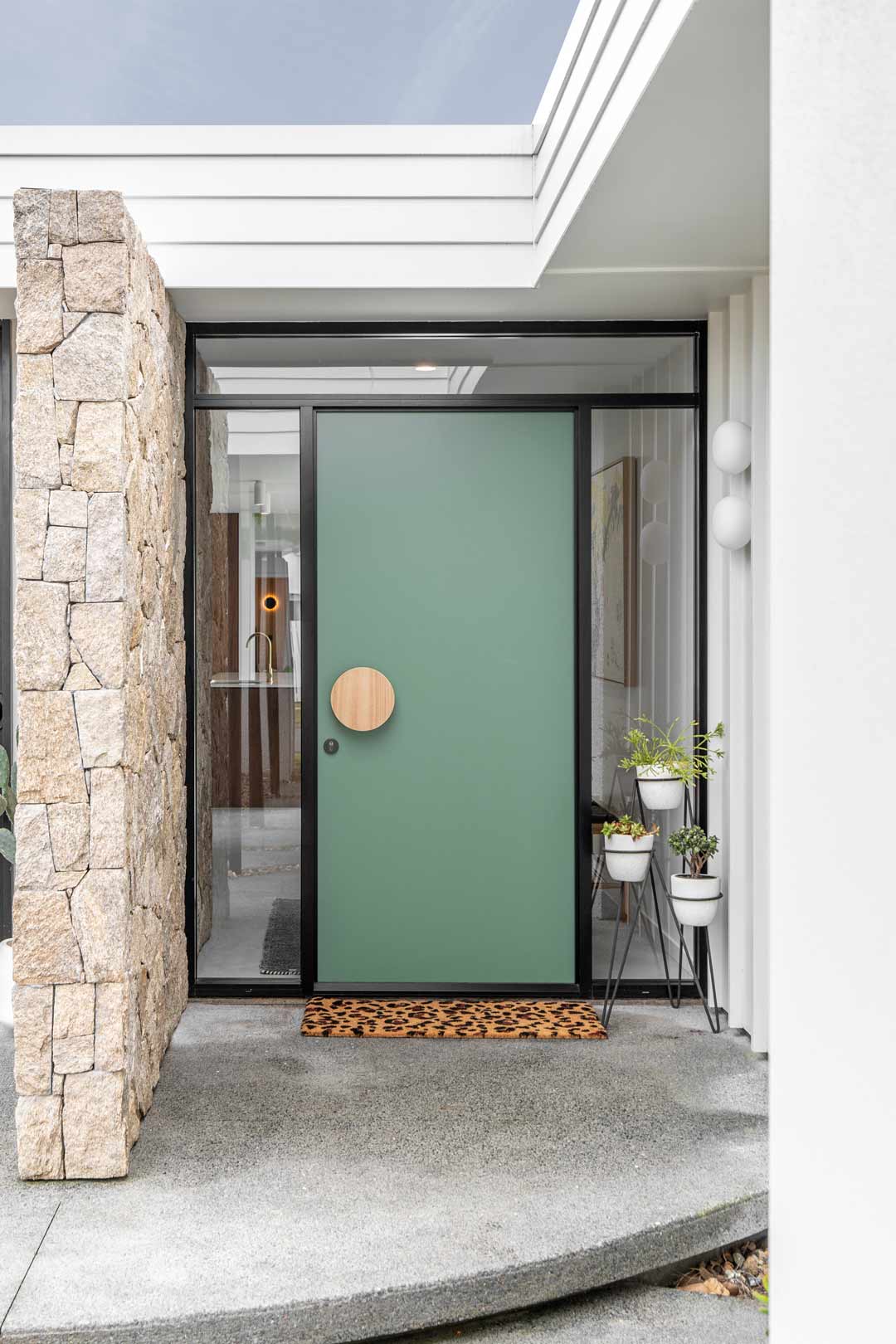 A-bright-green-statement-front-door-with-a-round-timber-door-handle