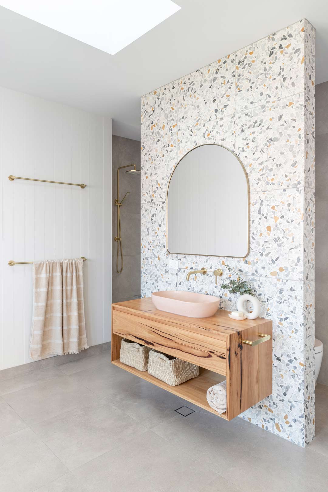 Coastal-bathroom-with-terrazzo-tiles-pink-concrete-basin-and-brushed-brass-tap-ware-1