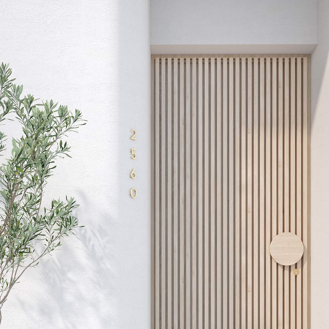 Stylish-brushed-brass-house-number-signage-on-a-white-rendered-front-entry-way-with-a-vertical-timber-panelled-door-and-round-door-handle